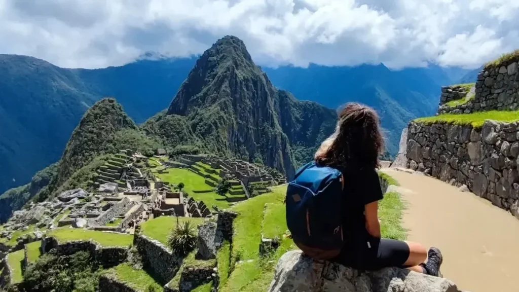 Traveler enjoying panoramic view of Machu Picchu from upper terrace with Huayna Picchu