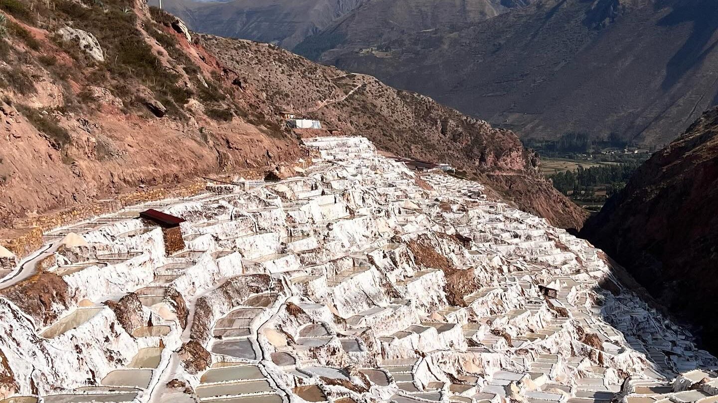 White terraced pools of Maras Salt Mines cascading down mountain in Sacred Valley Cusco