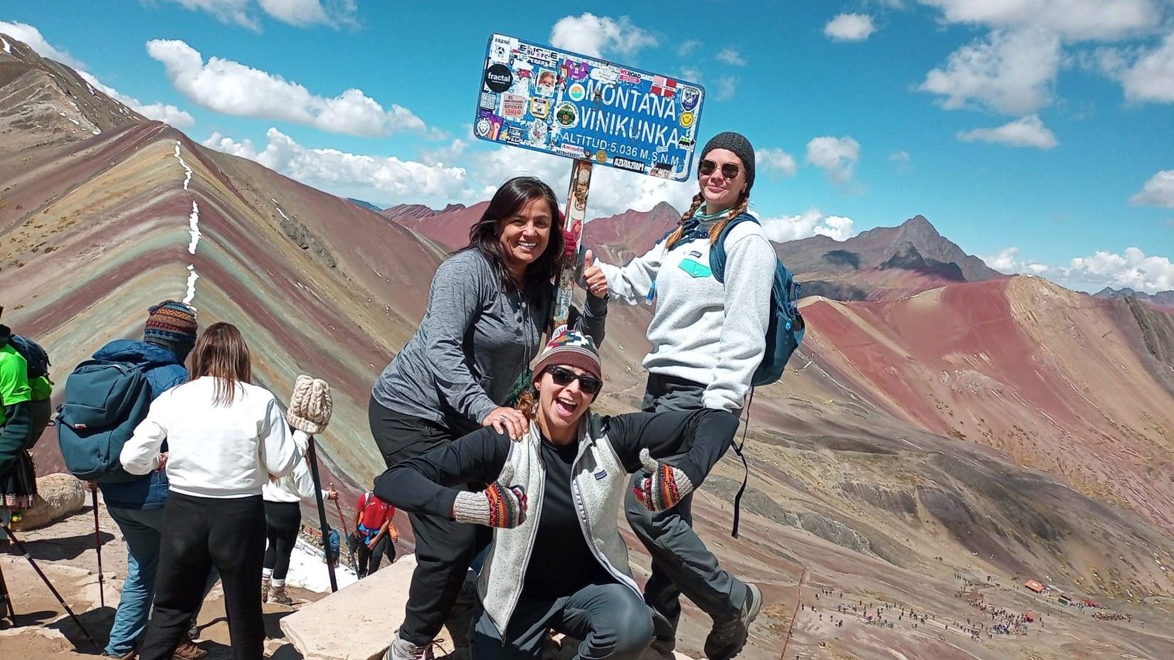 Hikers at Rainbow Mountain Vinicunca summit sign 5036m on the Rainbow Mountain Trek

