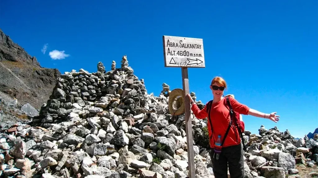 Traveler at Abra Salkantay sign marking 4600m altitude on Salkantay Pass 4650m final day of 5 Day City Tour Sacred Valley Machu Picchu and Humantay Lake trek